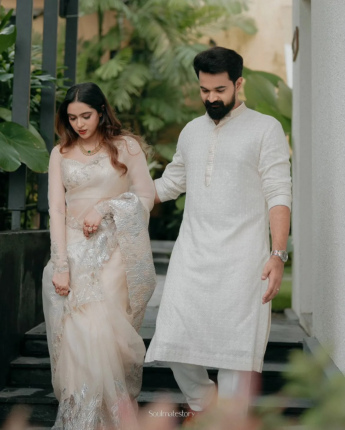 A couple walking together in traditional ivory wedding attire