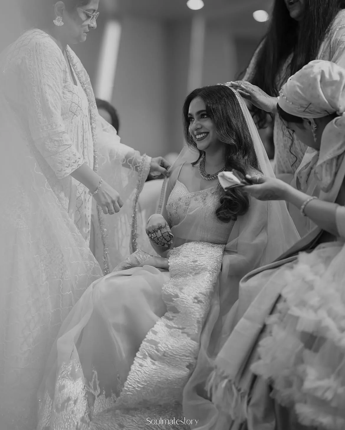 A smiling bride surrounded by friends while getting ready